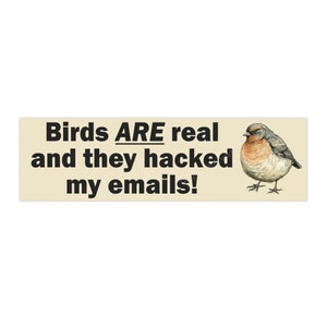 May include: A beige sticker with black text that reads "Birds ARE real and they hacked my emails!" and a cartoon illustration of a brown and gray bird.