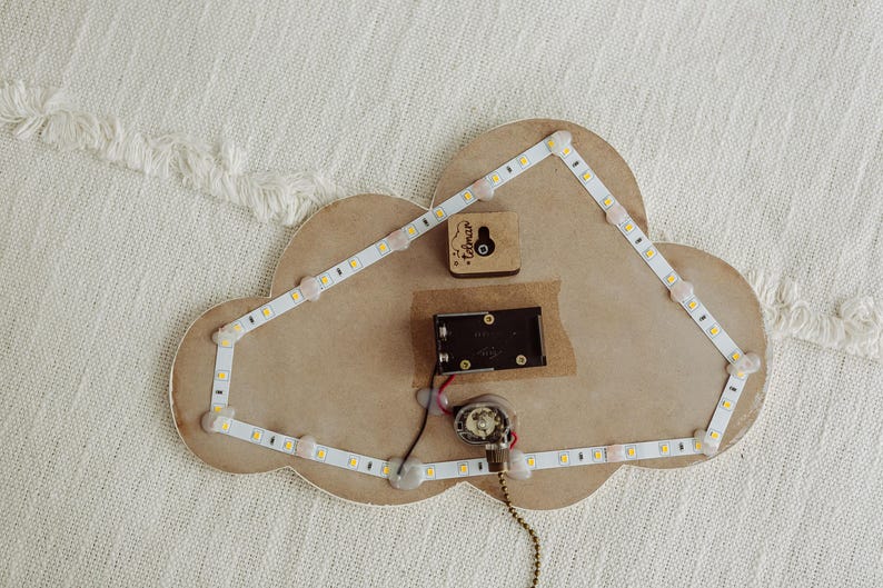 May include: A wooden cloud-shaped night light with a white LED strip around the edge. The light is wired to a small battery pack and a switch. The cloud has a small wooden heart with the word "Forever" inscribed on it.