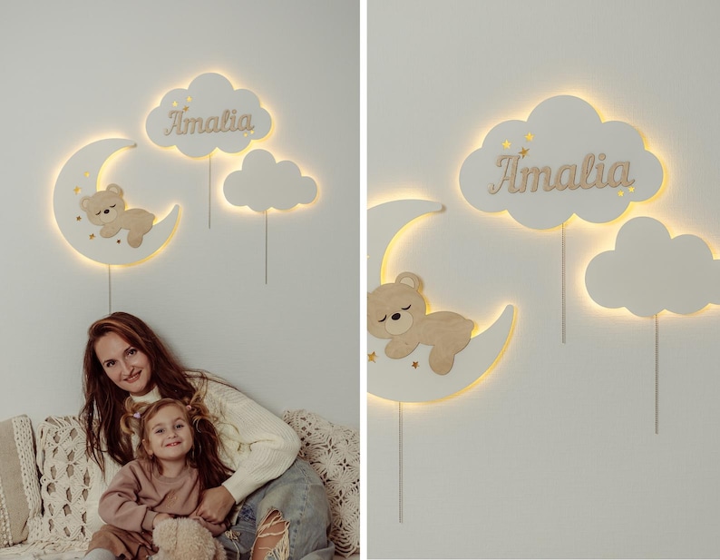 May include: A white wooden nightlight with a crescent moon, a cloud with the name "Amalia" and a cloud with a sleeping bear. The nightlight is illuminated with warm white LED lights.