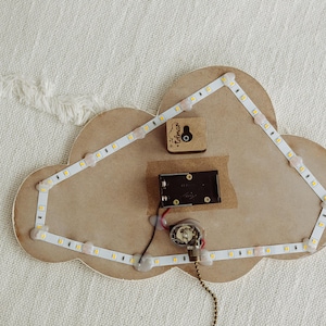 May include: A wooden cloud-shaped night light with a white LED strip around the edge. The light is wired to a small battery pack and a switch. The cloud has a small wooden heart with the word "Forever" inscribed on it.