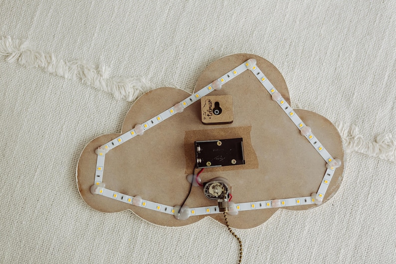May include: A wooden cloud-shaped night light with a white LED strip around the edge. The light is wired to a small battery pack and a switch. The cloud has a small wooden heart with the word "Forever" inscribed on it.