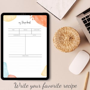 Pode incluir: Um tablet digital exibindo um modelo de receita com o título "my Recipe book". O modelo tem seções para o tempo, as porções, a temperatura de cozimento, os ingredientes, as notas e as instruções. O fundo do modelo é um design de aquarela com tons de laranja, amarelo e azul.