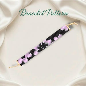 May include: A beaded bracelet featuring a black and lilac floral design. The bracelet has gold-coloured metal ends and a chain clasp. The words "Bracelet Pattern" are written in green script.