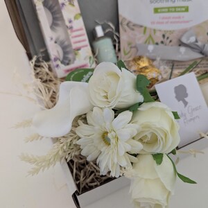 May include: A gift box filled with beauty products, including a package of false eyelashes, a face mask, and a small bottle. The box is decorated with white flowers and dried grass. The text "perfectgirl" and "Simple" are visible.