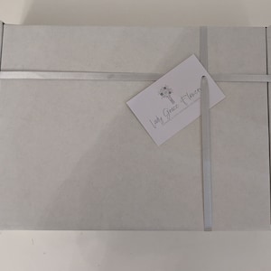 May include: A white gift box with a silver ribbon and a business card that reads "Lady Grace Flowers" with a floral design.