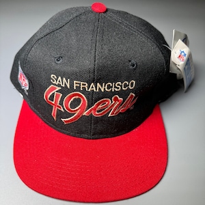 May include: Black and red baseball cap with the words "San Francisco 49ers" embroidered in gold on the front.