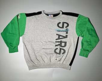 May include: Gray sweatshirt with black and green sleeves. The front of the sweatshirt has a vertical graphic that says "DALLAS STARS" in black.