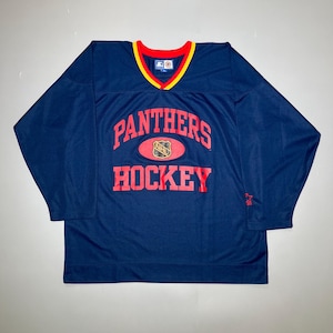 May include: A blue long-sleeved hockey jersey with the words "Panthers Hockey" in red and a red and gold NHL logo. The jersey has a red and yellow collar.