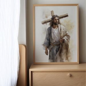 May include: A framed watercolour painting of a man carrying a wooden cross on his shoulders. The man is wearing a long robe and has a crown of thorns on his head. The painting is set against a light brown background.