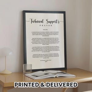 Peut inclure: Impression encadrée avec le texte "Technical Support's Prayer" en écriture élégante. Le cadre noir entoure un fond blanc avec le texte de la prière. L'expression "PRINTED & DELIVERED" est en bas. Un verre et un livre sont sur la table.