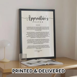 May include: A framed print with the text "Apprentice's Prayer" in elegant script. The black frame surrounds a white background with the prayer text. The words "PRINTED & DELIVERED" are at the bottom.