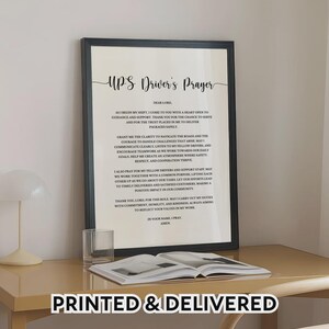 Peut inclure: Une impression encadrée avec la "Prière du Chauffeur UPS" en écriture élégante. Le cadre noir entoure le texte, centré sur un fond crème. Les mots "PRINTED & DELIVERED" sont en bas. Un verre et un livre sont sur la table.