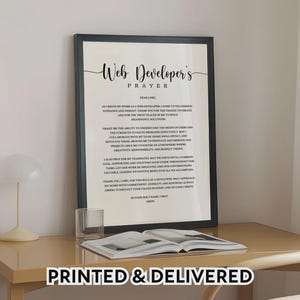 May include: A framed print with the text "Web Developer's Prayer" in elegant script. The black frame surrounds a white background with the prayer text. The words "PRINTED & DELIVERED" are at the bottom.