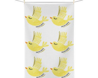 May include: White kitchen towel with a repeating pattern of yellow birds with the text "SOAR WITH PURPOSE" printed on each bird.