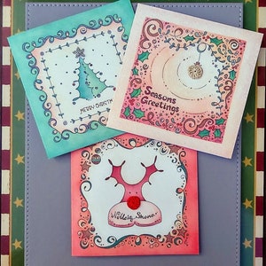 Three illustrated Christmas Cards, a Christmas tree with hand crocheted star; a Christmas bauble with hand crocheted bauble circle and a Christmas reindeer with hand crocheted red nose.