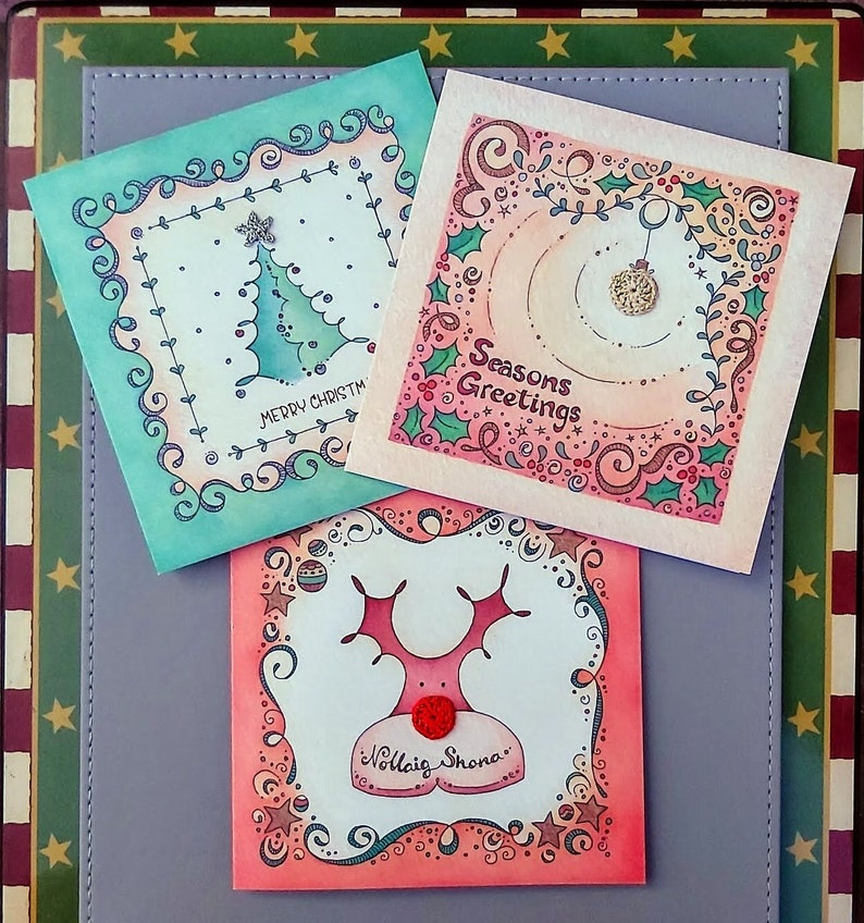 Three illustrated Christmas Cards, a Christmas tree with hand crocheted star; a Christmas bauble with hand crocheted bauble circle and a Christmas reindeer with hand crocheted red nose.