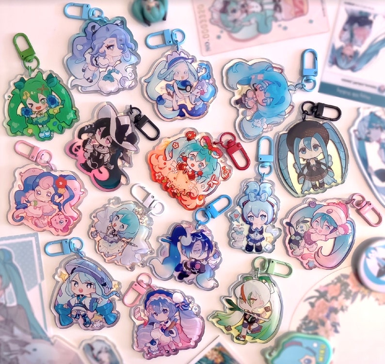 May include: A collection of 15 colorful anime character keychains with silver metal rings. The keychains feature various characters with different hairstyles, clothing, and accessories. The keychains are made of clear acrylic and have a holographic finish.