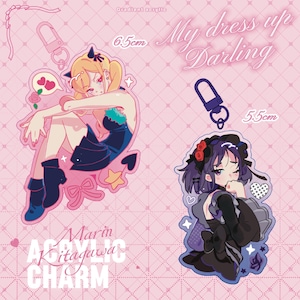 May include: Two acrylic charms featuring anime-style illustrations of female characters. One charm is 6.5cm and the other is 5.5cm. The charms have keychains and are on a pink background with text that reads "My Dress Up Darling" and "Marin Kitagawa Charm".