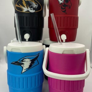 May include: Four insulated beverage coolers in black, red, blue, and pink, each with a white lid and handle. The coolers feature team logos: a tiger, a bee, a blue jay, and a blank design. Each has a clear straw.