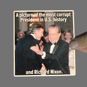 May include: A sticker featuring a photograph of two men in suits shaking hands. The text on the sticker reads, "A picture of the most corrupt President in U.S. history and Richard Nixon."