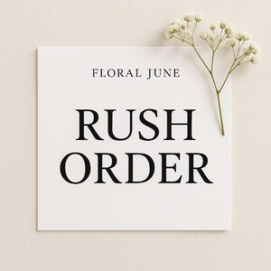 May include: A white square card with the text "FLORAL JUNE" at the top and "RUSH ORDER" in large, bold, black letters. A sprig of white flowers is placed on the upper right corner of the card.