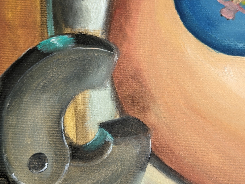 May include: A close-up of a black metal object with a teal accent. The object has a rounded shape and a textured surface. It is partially obscured by a light brown background.