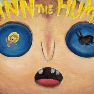 May include: A close-up of a painting depicting a face with two large blue eyes. The left eye shows a reflection of a woman with blonde hair, while the right eye shows a reflection of a black silhouette of a rabbit. The text "FINN THE HUMAN" is written in yellow across the top of the image.