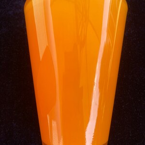May include: A bright orange glass vase with a rounded bottom and a flared top.