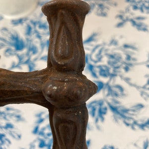 May include: Close-up of a rusty, ornate metal handle with a decorative finial. The handle is likely for a door or gate.