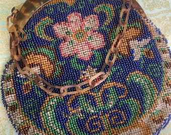 May include: A vintage beaded purse with a floral design in shades of blue, green, pink, and gold. The purse has a tortoise shell frame and a chain strap.