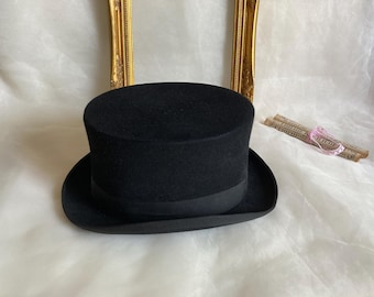 May include: A black top hat with a wide brim. The hat is made of felt and has a smooth, polished finish.