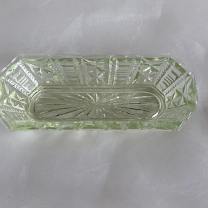 Könnte beinhalten: Eine klare Glasschale mit einem geschliffenen Glasdesign. Die Schale ist rechteckig mit abgerundeten Kanten und hat eine leicht erhöhte Mitte.