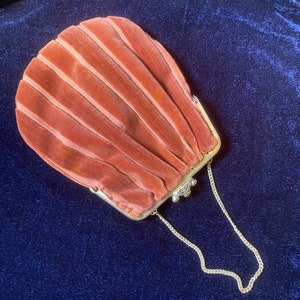 May include: A vintage, pleated, peach-colored velvet purse with a silver chain and clasp.