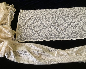 May include: A set of two off-white lace curtains with a floral pattern. The curtains are made of delicate lace and have a scalloped edge.