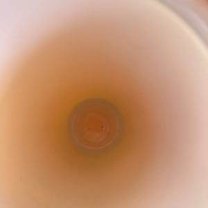 May include: A white ceramic mug with a smooth, glossy finish. The inside of the mug is visible, showing a light brown color.