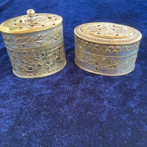 Peut inclure: Deux boîtes à bijoux anciennes en laiton avec des motifs floraux complexes. Les boîtes sont de forme ovale et ronde et ont une finition vieillie.