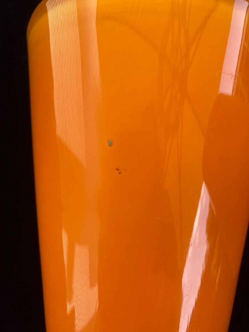 May include: A bright orange glass vase with a smooth, shiny finish. The vase has a wide mouth and a narrow base.
