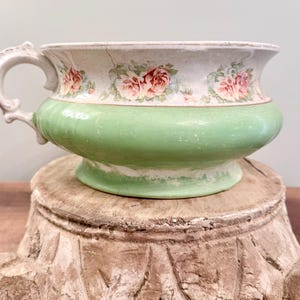 アンティークの陶器、おそらく鉄鉱石製の便器。パステルグリーンとクリーム色にピンクの花柄模様。