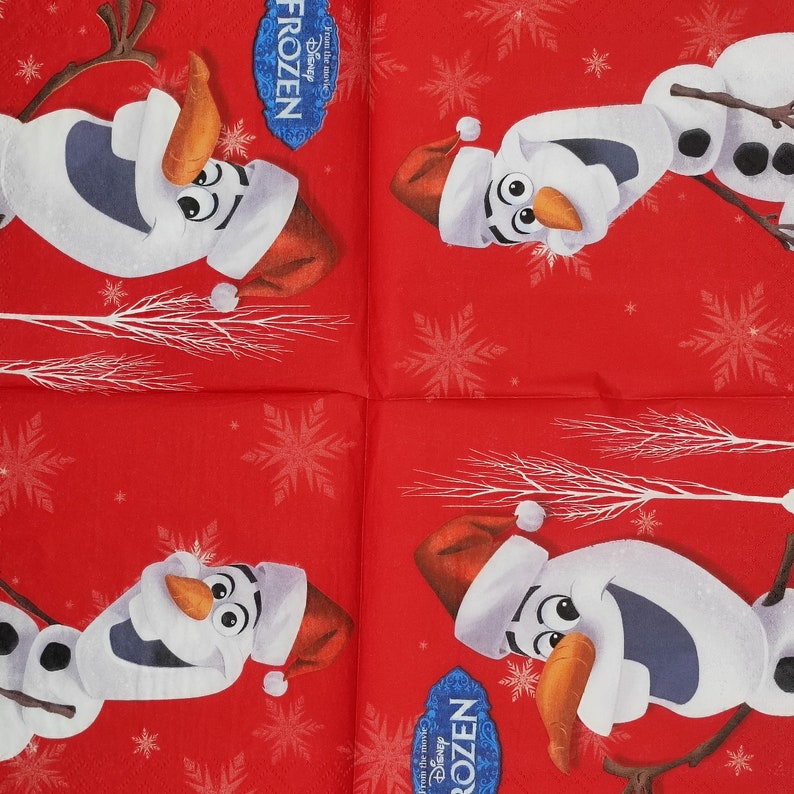 Puede incluir: Cuatro servilletas rojas con un patr&oacute;n de copo de nieve blanco. Cada servilleta presenta una imagen de dibujos animados de Olaf de la pel&iacute;cula Frozen con un gorro de Pap&aacute; Noel. El texto "Frozen" y "From the movie" est&aacute; impreso en las servilletas.