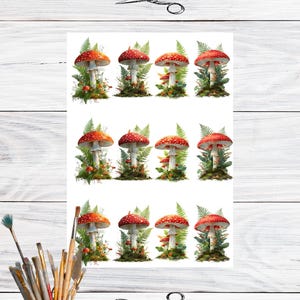May include: A sheet of stickers featuring watercolor illustrations of red and white spotted mushrooms with green foliage. The stickers are arranged in three rows of four. A small cup of paintbrushes and a pair of scissors are also visible.