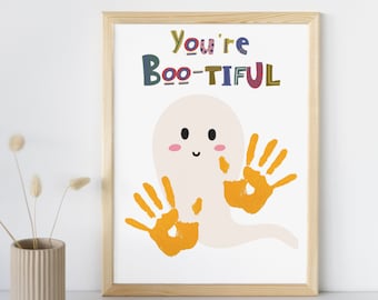 以下が含まれることがあります： オレンジ色の手形と「You're Boo-tiful」というテキストが書かれた白い幽霊が描かれた、ハロウィーンをテーマにした印刷可能なアートプリントです。