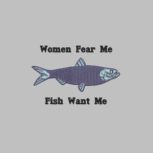 May include: A gray background with the embroidered text "Women Fear Me" above a purple fish illustration. Below the fish, the text reads "Fish Want Me". The fish has blue accents.