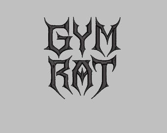 May include: Black embroidered text on a gray background reads "GYM RAT" in a gothic font. The letters are stylized with sharp, pointed serifs, giving a bold and edgy appearance. The design is centered.