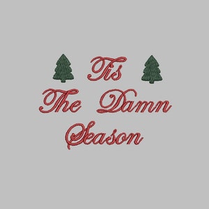 May include: Red embroidered text on a white background that reads "Tis the Damn Season" with two green embroidered Christmas trees on either side of the text.