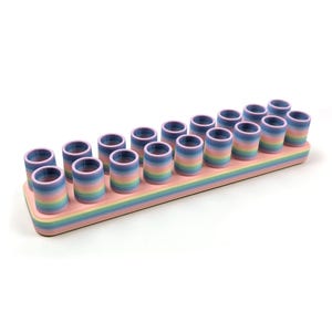 May include: A rainbow-coloured plastic organiser with 18 slots for storing small items. The organiser is made of a light pink plastic with blue, yellow, and green stripes.