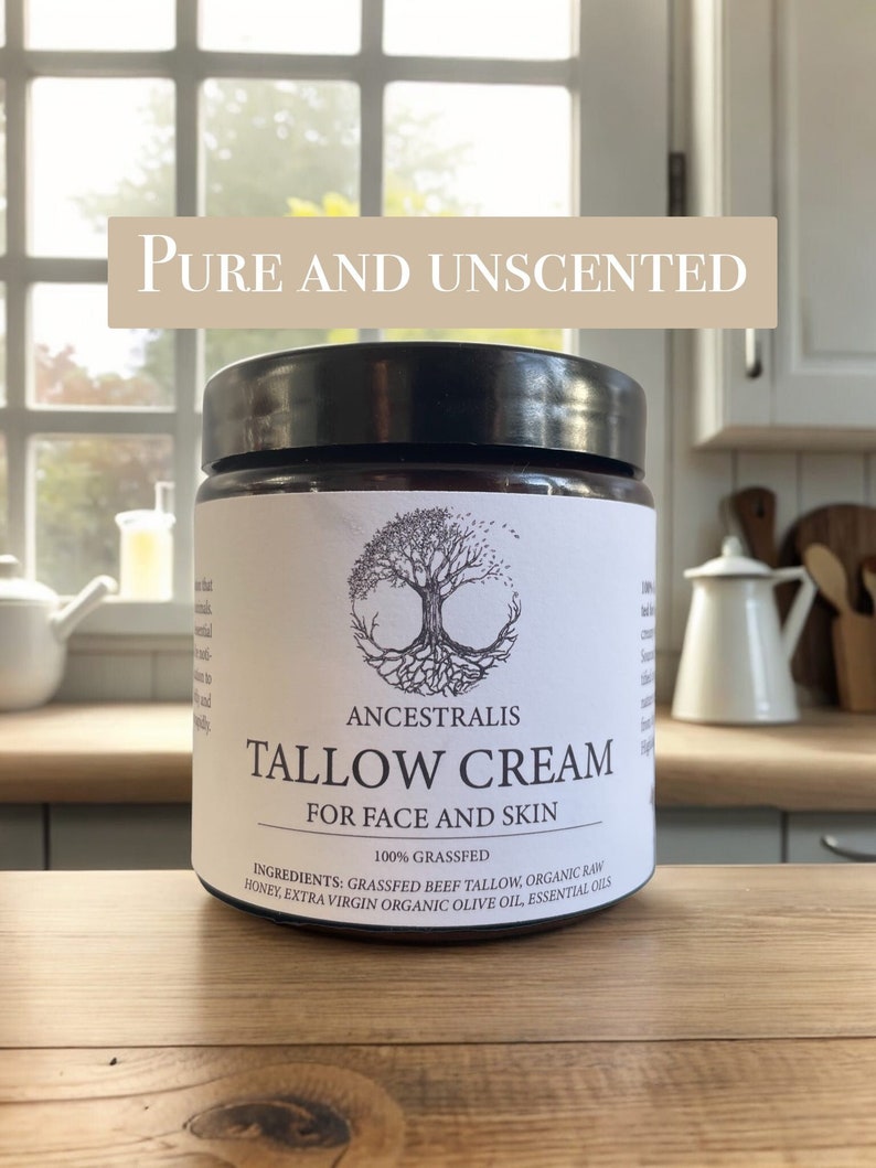 Peut inclure: Un pot blanc avec un couvercle noir et une &eacute;tiquette qui indique "Ancestralis Tallow Cream for Face and Skin 100% Grassfed". L'&eacute;tiquette comprend &eacute;galement les ingr&eacute;dients : "Suif de b&oelig;uf nourri &agrave; l'herbe, miel brut biologique, huile d'olive biologique extra vierge, huiles essentielles".