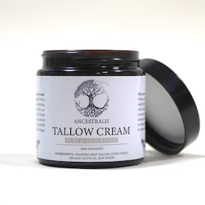 Peut inclure: Un pot en verre avec un couvercle noir contenant une cr&egrave;me de suif blanche non parfum&eacute;e. L'&eacute;tiquette indique "Ancestralis Tallow Cream Pure & Unscented 100% Grassfed Ingredients: Grassfed Beef Tallow, Extra Virgin Organic Olive Oil, Raw Honey".