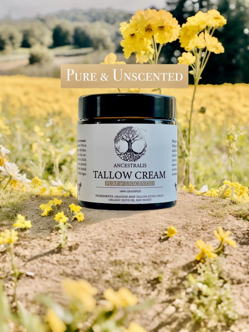 Peut inclure: Un pot en verre de cr&egrave;me de suif non parfum&eacute;e avec une &eacute;tiquette blanche qui indique "ANCESTRALIS TALLOW CREAM PURE & UNSCENTED 100% GRASSFED INGREDIENTS: GRASSFED BEEF TALLOW, EXTRA VIRGIN ORGANIC OLIVE OIL, RAW HONEY". Le pot est pos&eacute; sur une surface brune avec des fleurs jaunes.
