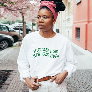 Pu&ograve; includere: Felpa bianca a maniche lunghe con testo verde che recita "Hit 'em low Hit 'em high".