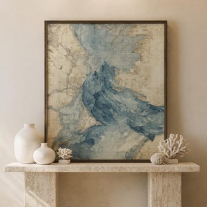 May include: A framed watercolour map print in blue and beige tones, showing a coastal area. The artwork is displayed on a stone console table, with white vases and coral sculptures. The style is coastal and serene, with a calming atmosphere.